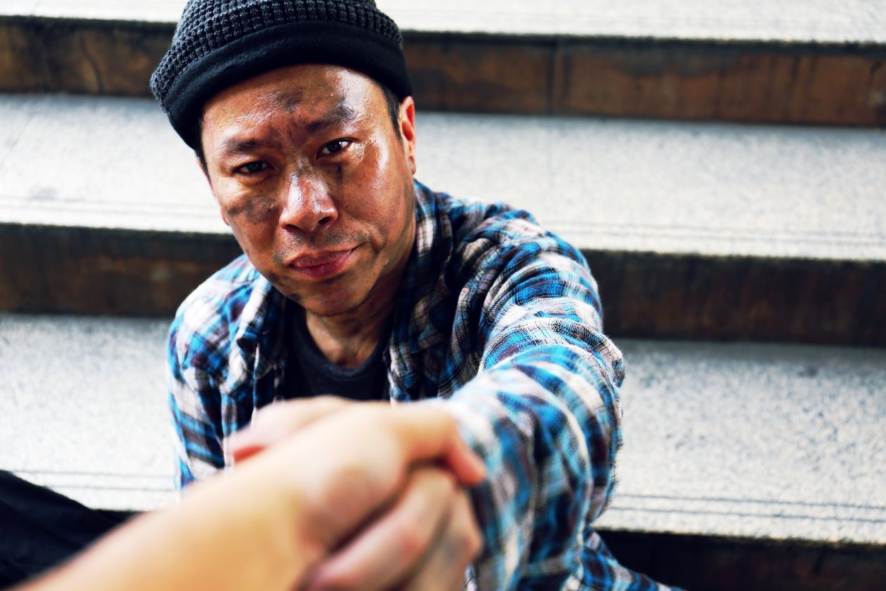 Close-up handshake for help homeless man on walking street in the capital city